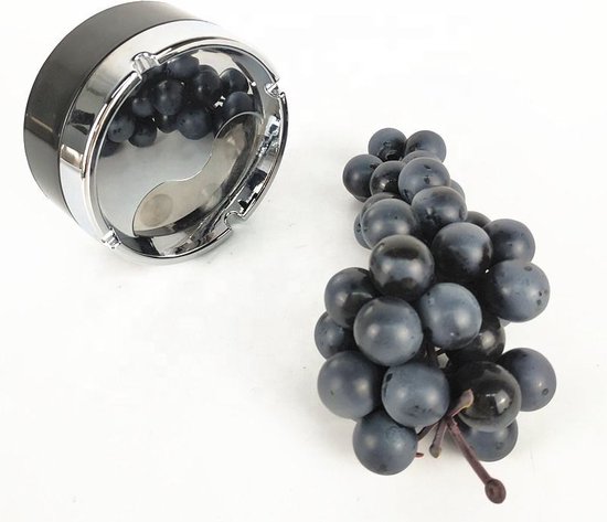 Zwarte draaiasbak met yin-yang motief en chroomkleurige rand, naast een tros donkerblauwe druiven.