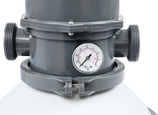 Close-up van een manometer op de grijze bovenkant van een zandfilterpomp, met witte slangaansluitingen.