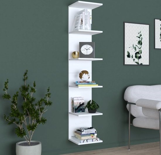 Witte, smalle wandkast met 6 legplanken, gevuld met boeken, een klok en decoraties.
