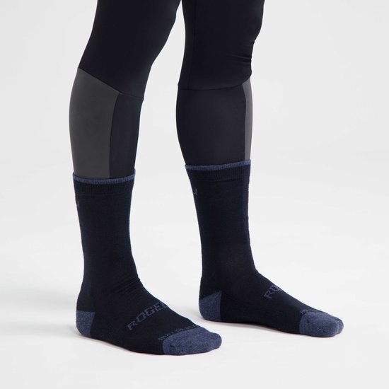 Een persoon draagt een donkerblauwe fietssok met donkergrijze teen en hiel, boven een zwarte fietsbroek.