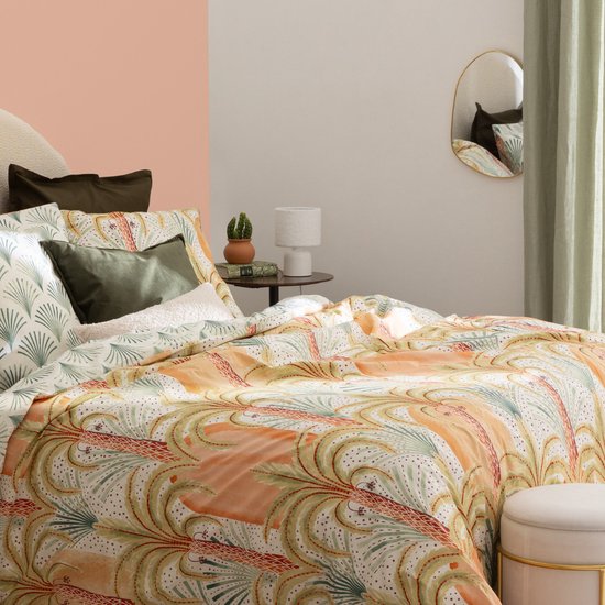 Gouden spiegel in organische vorm, reflecteert een slaapkamer met een gestreept bed.