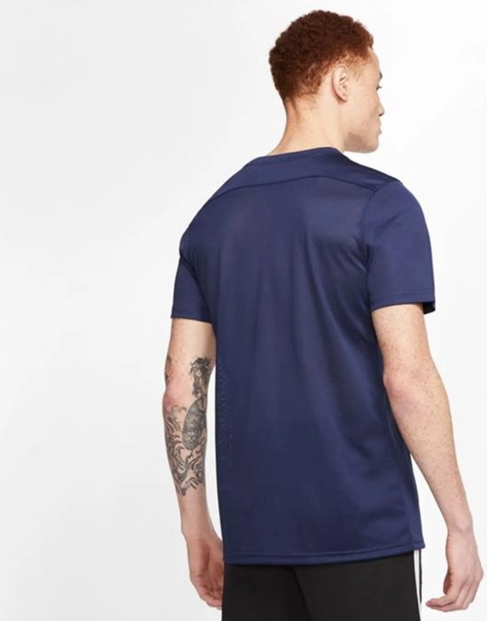 Man met kort rood haar, gezien van achteren, draagt een marineblauw sportshirt met korte mouwen.