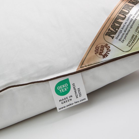 Detail van wit kapok kussen met bruine bies en Oeko-Tex label.