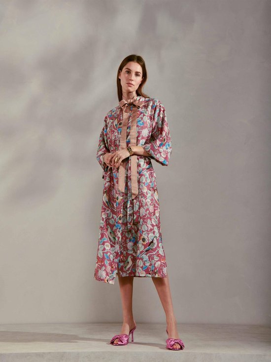Vrouw in paarse kimono met bloemen- en vogelprint, ceintuur in de taille, strik in de nek.
