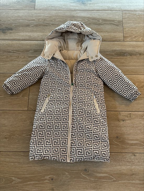 Lange jas met capuchon, beige met geometrisch patroon in zwart en wit. Rits middenvoor.