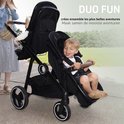 Zwarte tweeling kinderwagen met twee zittende kinderen, een jongen vooraan en een baby achteraan.