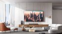 Zwarte soundbar en subwoofer, geplaatst voor een grote tv in een modern ingerichte woonkamer.