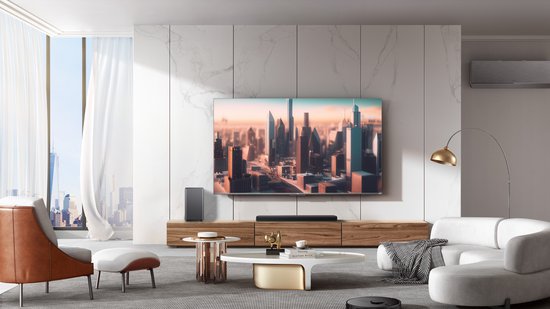 Zwarte soundbar en subwoofer, geplaatst voor een grote tv in een modern ingerichte woonkamer.