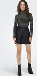 Vrouw met lang bruin golvend haar, draagt een gestreepte grijze coltrui en zwarte faux leren shorts.