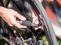 Handen gebruiken een zilveren CO2-patroon met zwarte hoes om een fietsband op te pompen.