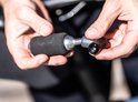 Handen houden een zilveren CO2-patroon met zwarte schuimhoes en adapter vast.