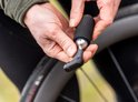 Handen houden een zilveren CO2-patroon met zwarte schuimhoes en BBB-adapter vast.