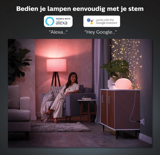 Vrouw zit op een bank in een woonkamer met Philips Hue verlichting. Alexa en Google Assistant logo's.