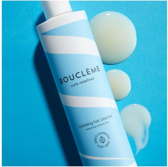 Fles hydraterende haarreiniger met blauwe en witte strepen, met drie druppels product ernaast op een blauwe achtergrond.
