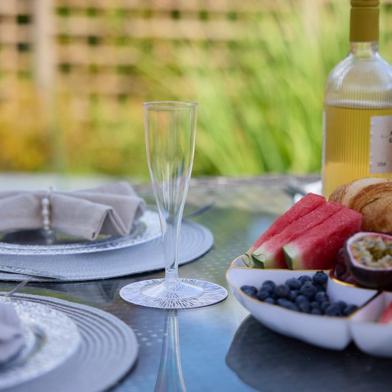 Lege champagneflûte op een tafel met fruit en een fles witte wijn.