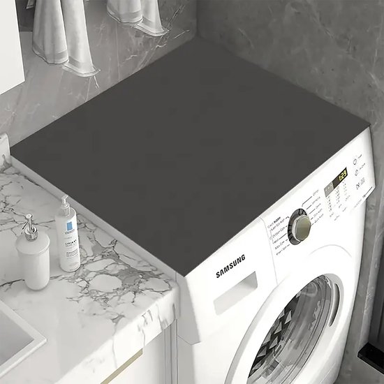 Zwarte beschermmat op de bovenkant van een Samsung wasmachine in een badkamer.