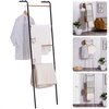 Collage van een zwarte ladder met houten treden, met kleding en dekens, in verschillende interieuropstellingen.