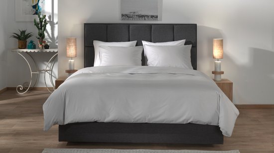 Een opgemaakt bed met Vaporous Grey dekbedovertrek en witte kussens.