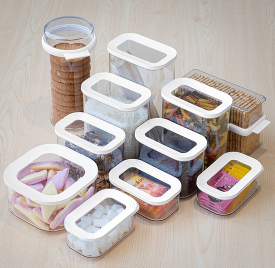 Ensemble de boîtes de rangement Mepal remplies de pâtes, riz, céréales, biscuits, bonbons et croûtons, sur fond en bois.