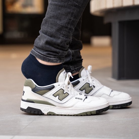 Donkerblauwe SOLIT enkelsok gedragen met een witte sneaker.
