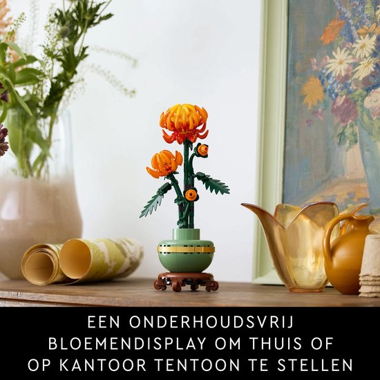 Affichage de chrysanthème LEGO dans un pot vert pastel sur un socle en bois, avec une toile et des vases.