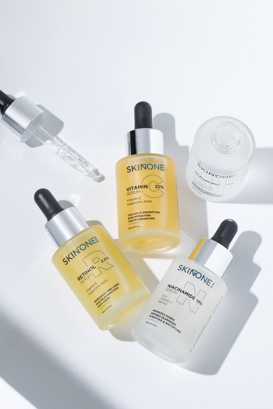 Vier SKINTONE serumflessen: vitamine C 20%, retinoïden 2,5%, niacinamide 10% en hyaluronzuur 2,5%. Geel, wit en transparant.