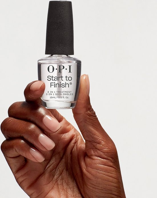 Een donkere hand houdt een flesje O.P.I. Start to Finish 3-in-1 nagelbehandeling van 15 ml vast. De nagellak is helder en heeft een zwarte dop.