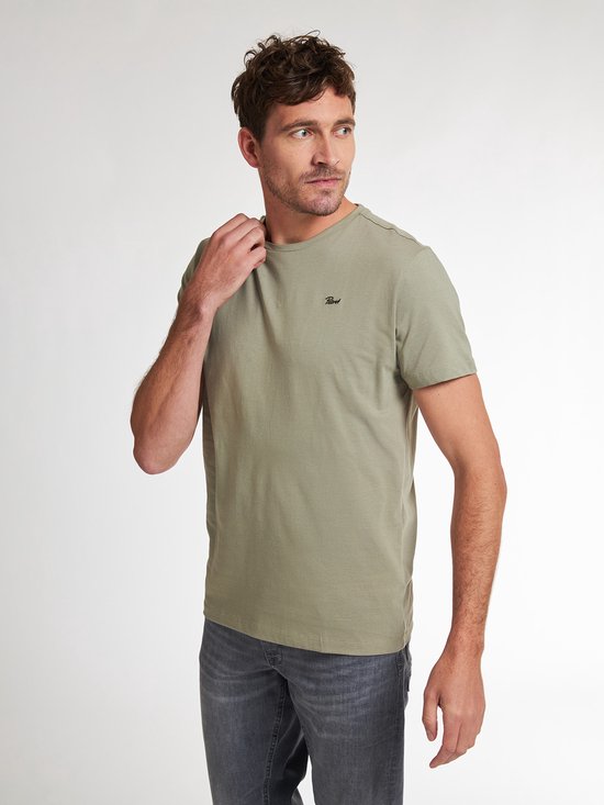 Man met groen t-shirt met korte mouwen en een ronde hals, die aan de kraag trekt.