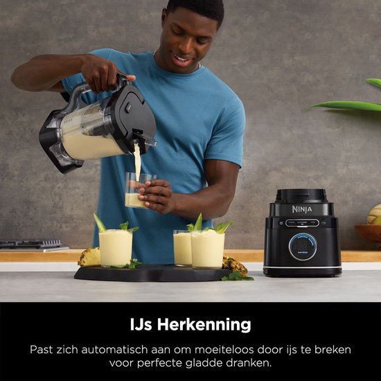 Man schenkt romige drank uit blender in glas, met drie glazen, ananas en Ninja blender ernaast.