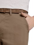 Hand in de zak van een bruine chino broek met riem.