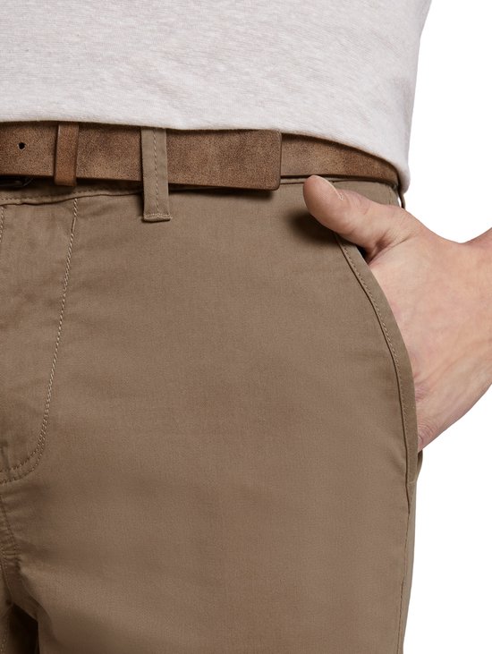 Hand in de zak van een bruine chino broek met riem.