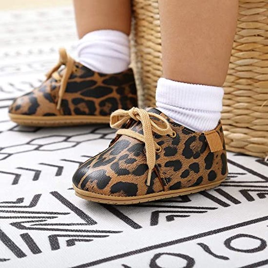 Voetjes van een baby in bruine schoenen met panterprint en witte sokken.
