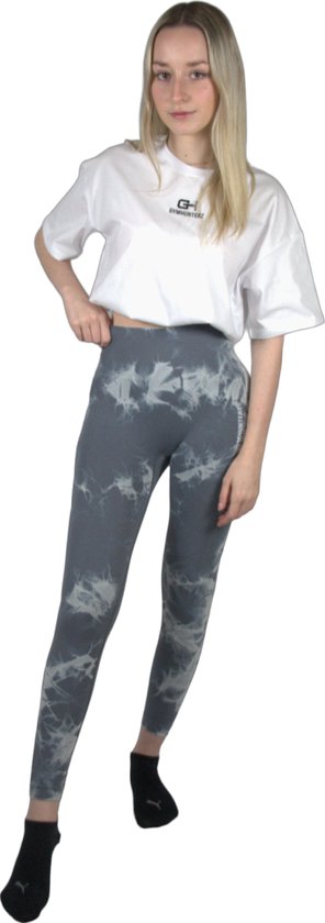 Model in een witte crop top en grijze legging met tie-dye print. De legging heeft Gymhunterz logo.