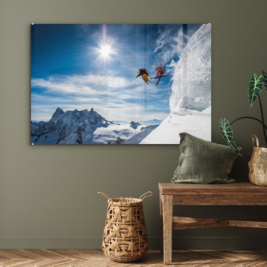 Glasschilderij van twee skiërs die van een berg in de sneeuw springen, hangend aan een muur.