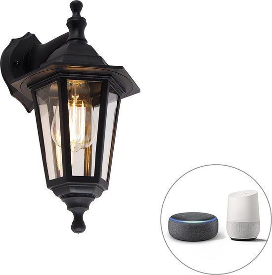 Zwarte klassieke wandlamp voor buiten, met glas en zichtbaar lampje. Naast de lamp staan een Amazon Echo Dot en een Google Home apparaat.