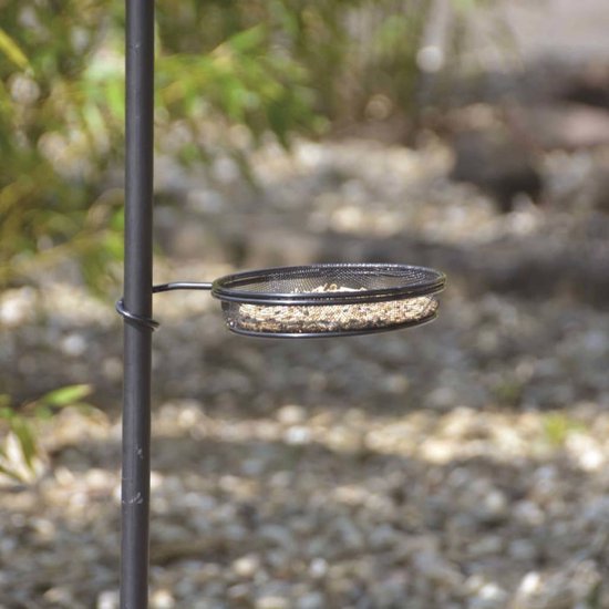 Detail van een zwart vogelvoederbakje gevuld met vogelvoer.