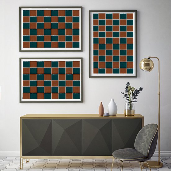 Trois œuvres d'art encadrées avec un motif à damier marron et vert sont suspendues au-dessus d'une commode gris foncé.