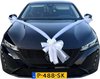 Zwarte auto met witte strikken en rozen op de motorkap, frontaal aanzicht.