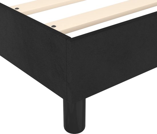 Detail van een zwart bedframe met houten latten en een zwarte poot.