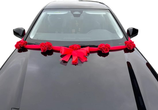 Zwarte auto met een rode strik en rozen op de motorkap, frontaal zicht.