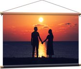 Textielposter - Silhouet van Koppel Hand in Hand bij de Zee tijdens Zonsondergang - 90x60 cm Foto op Textiel