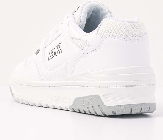 Achterkant van witte lage sneaker met grijze zolen en perforaties.