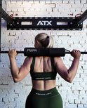 Vrouw met staartje in donkergroene sportkleding doet een squat met halterstang en zwarte pad met 'BREAKING LIMITS'.