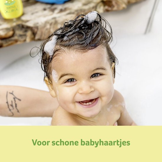 Een blije baby in bad met sop op het haar. Tekst: Voor schone babyhaartjes.