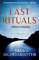 Boekomslag van 'Last Rituals', een spannende roman met de titel in rode en witte letters op een blauwe, wazige achtergrond met een weg die naar de horizon leidt.
