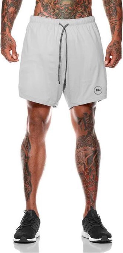Homme aux jambes tatouées portant un short de sport MW blanc.