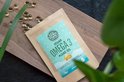 Bruine papieren zak van 'Ekopura Vegan Omega 3 Algae Oil' op een houten plank, omringd door goudkleurige capsules.