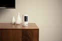 Witte Ring Stick Up Cam op een houten kast naast twee witte vazen.