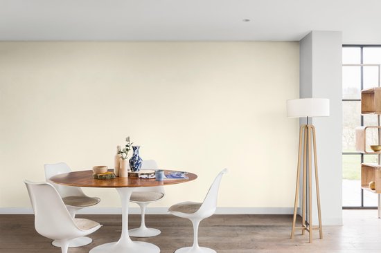 Witte eetkamerstoelen aan een ronde tafel in een kamer met vloerlamp.