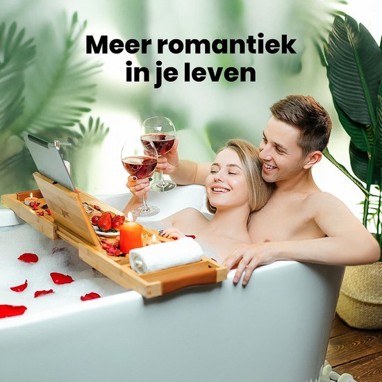 Romantisch bad met een stel, kaarsen, rozenblaadjes, fruit en een bamboe badplank.